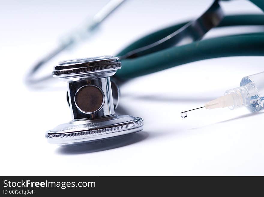 Stethoscope and a syringe in green on an isolated white background