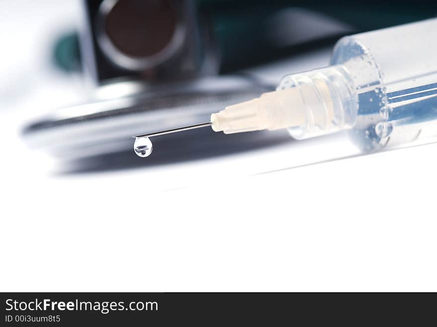 Stethoscope and a syringe in green on an isolated white background