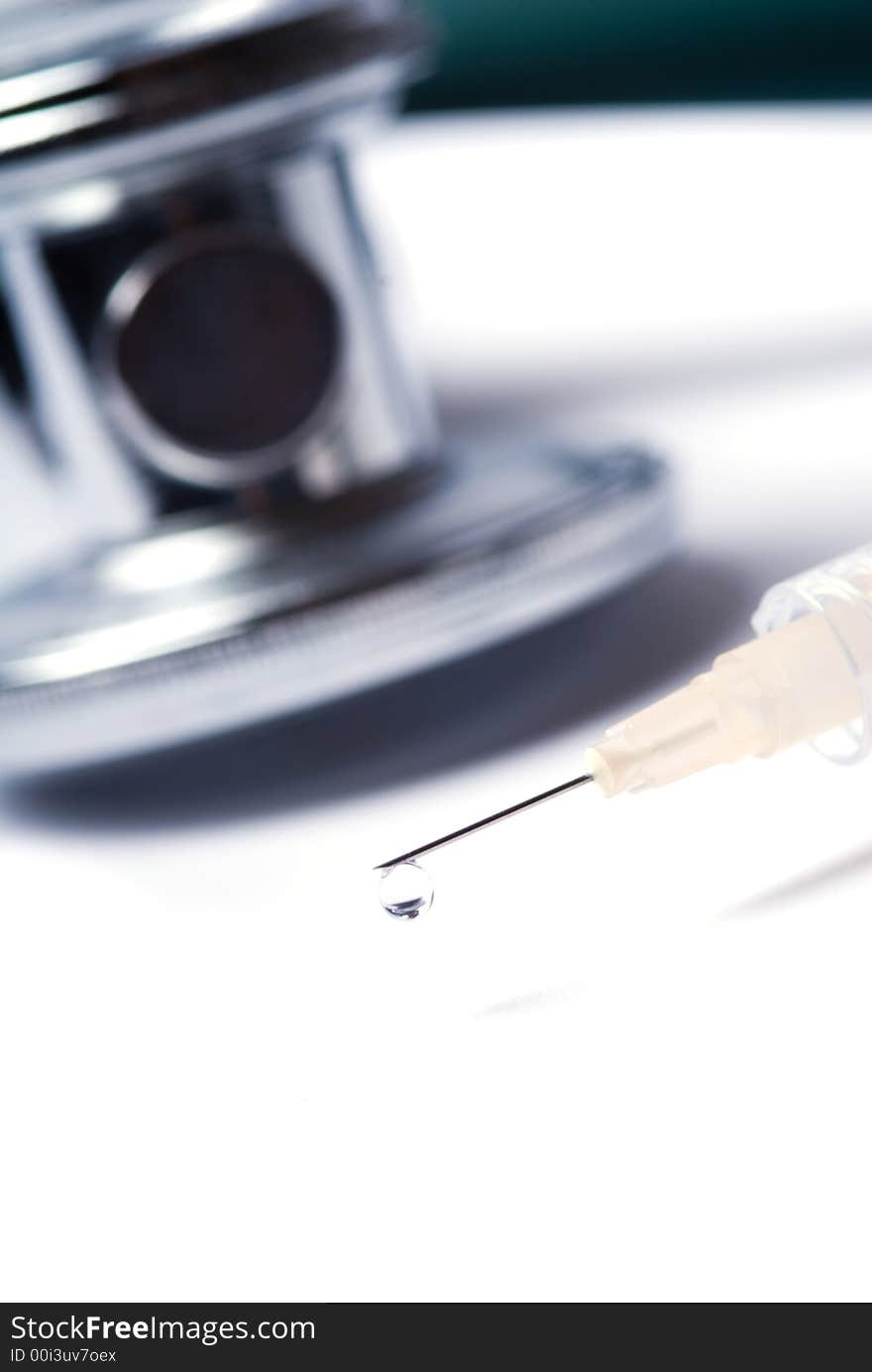 Stethoscope and a syringe in green on an isolated white background