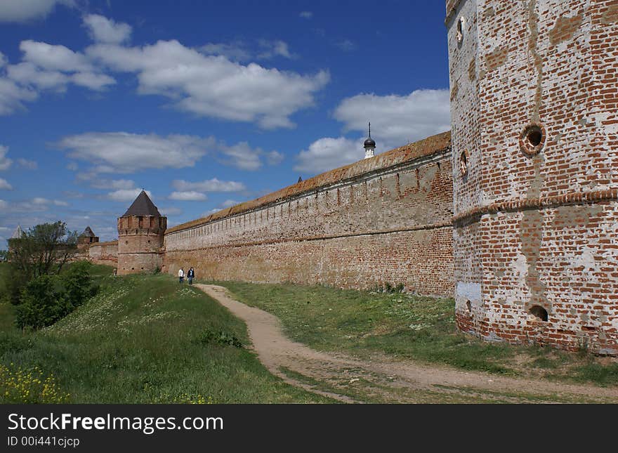 Long red fort wall with path along it. Summer, sunny day. Old Russian Town. Long red fort wall with path along it. Summer, sunny day. Old Russian Town