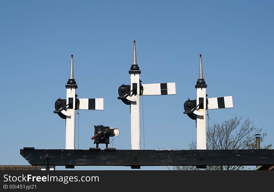 Railway signals set across the railway tracks against a blue sky