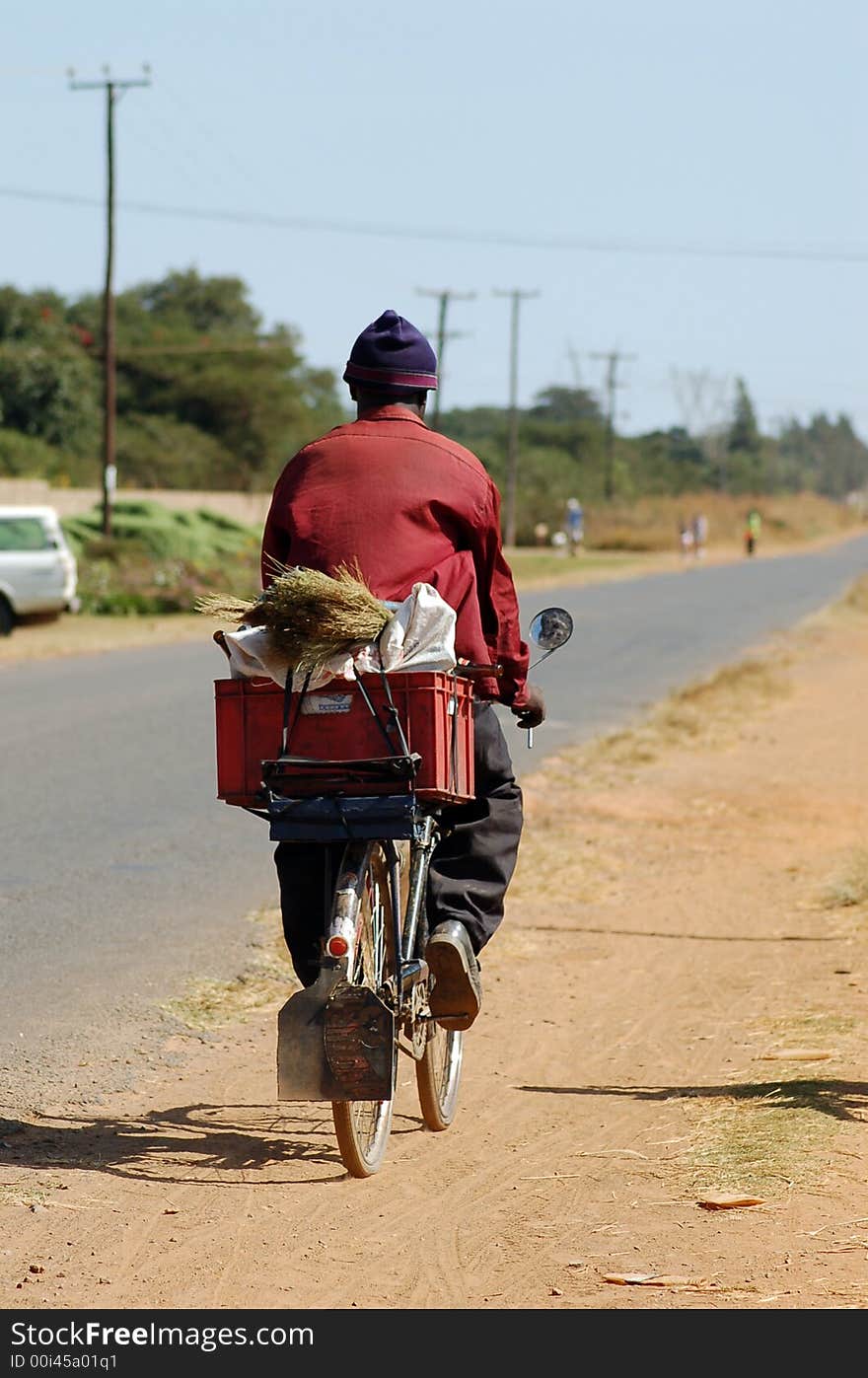 An african man transporting goods on a bicycle