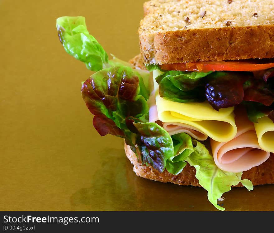 Wholebread sandwich with ham and cheese on brown background