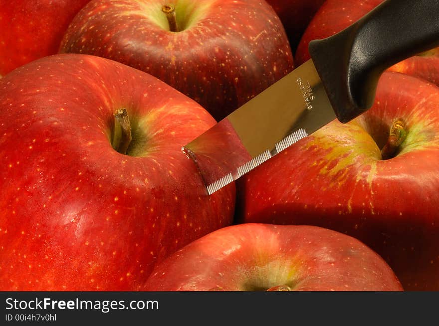 Image shows red apples with a stainless steel kitchen knife. Image shows red apples with a stainless steel kitchen knife