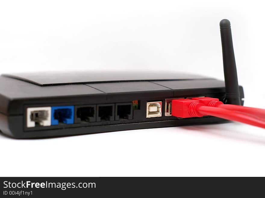 Backsite of a router isolated on white background. Two of the ports have red network cables plugged in. Backsite of a router isolated on white background. Two of the ports have red network cables plugged in.