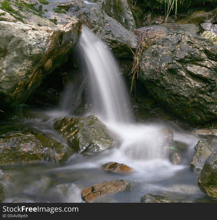 A long exposure of a small waterfall with misty water flow effect. A long exposure of a small waterfall with misty water flow effect