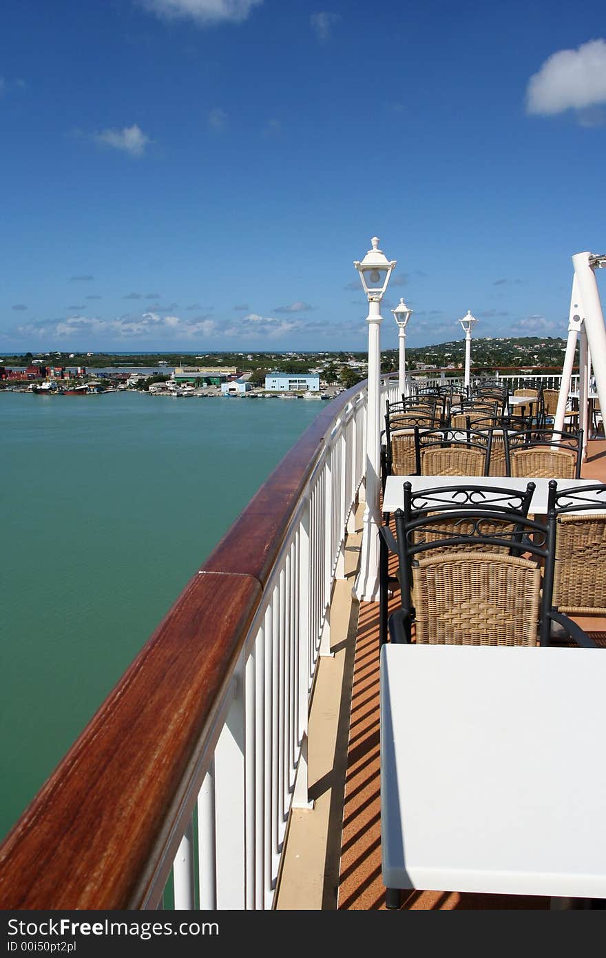 View of a cruise ship outdoor cafe with a view of a caribbean bay and coastal town. View of a cruise ship outdoor cafe with a view of a caribbean bay and coastal town.