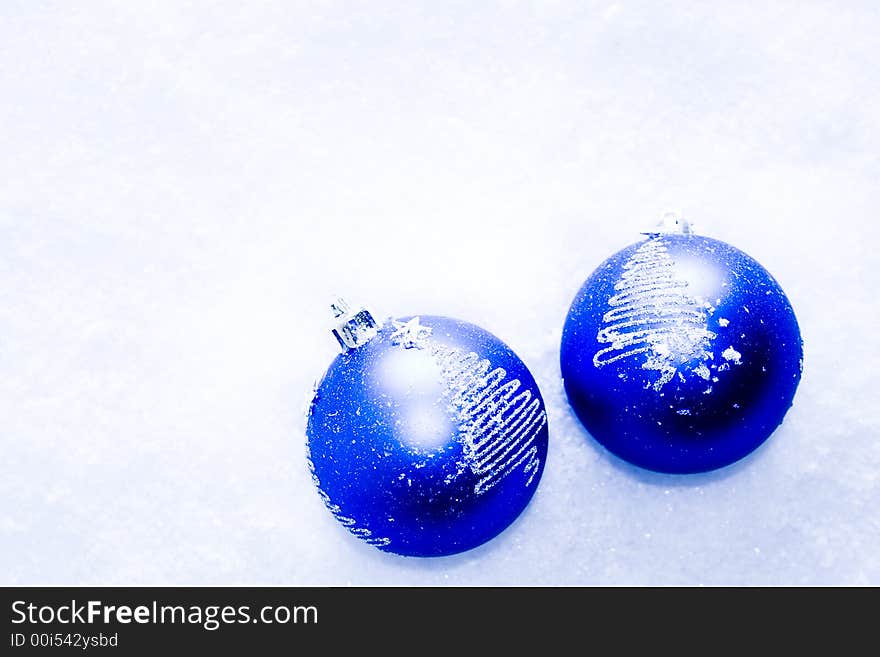 Two blue glass holiday ornaments in the snow. Two blue glass holiday ornaments in the snow.