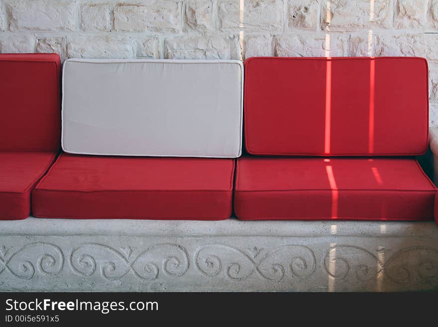 Nice contrast white and red cushions in a cozy summer house with white walls in the background. Nice contrast white and red cushions in a cozy summer house with white walls in the background...