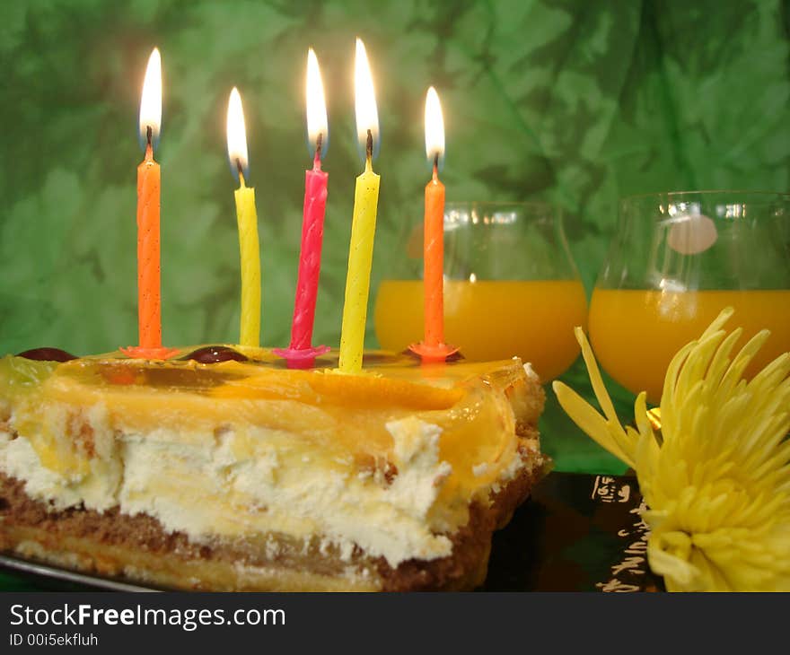 Celebratory table (cake and candles, two glasses) on green