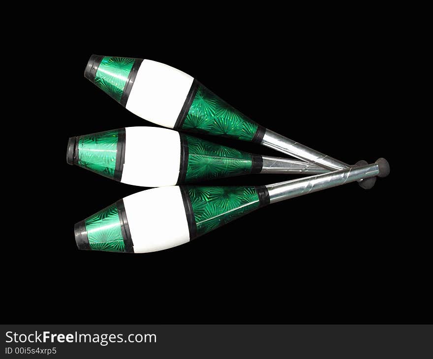 Three silver, green, black and white juggling clubs isolated on black background. Three silver, green, black and white juggling clubs isolated on black background