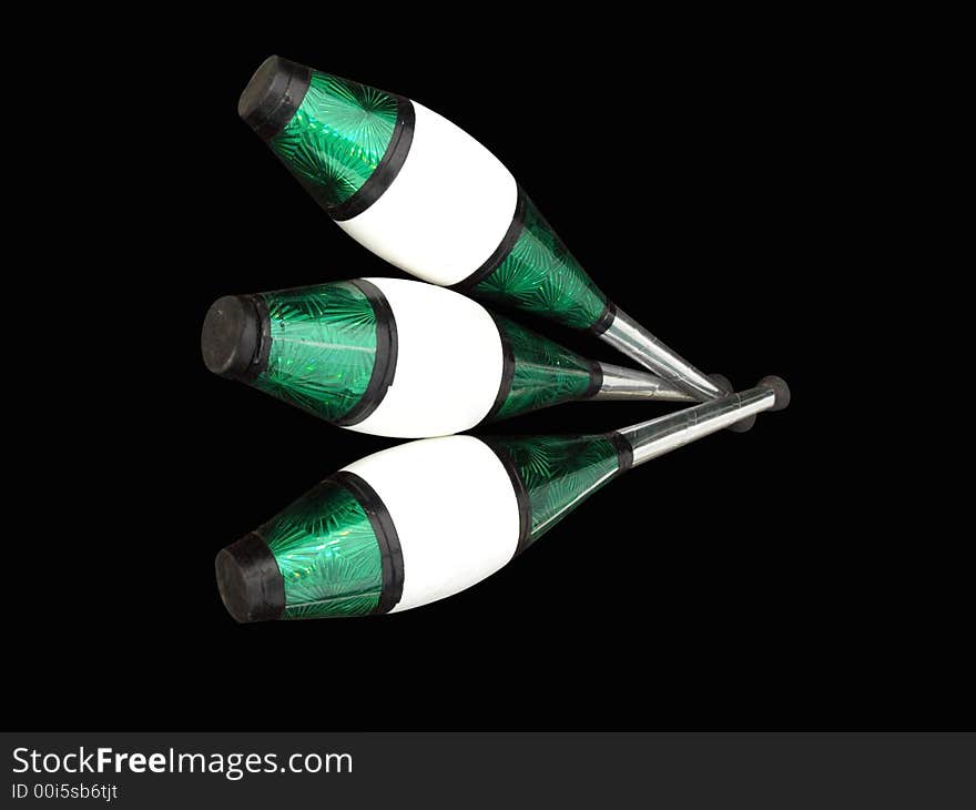 Three silver, green, black and white juggling clubs isolated on black background. Three silver, green, black and white juggling clubs isolated on black background