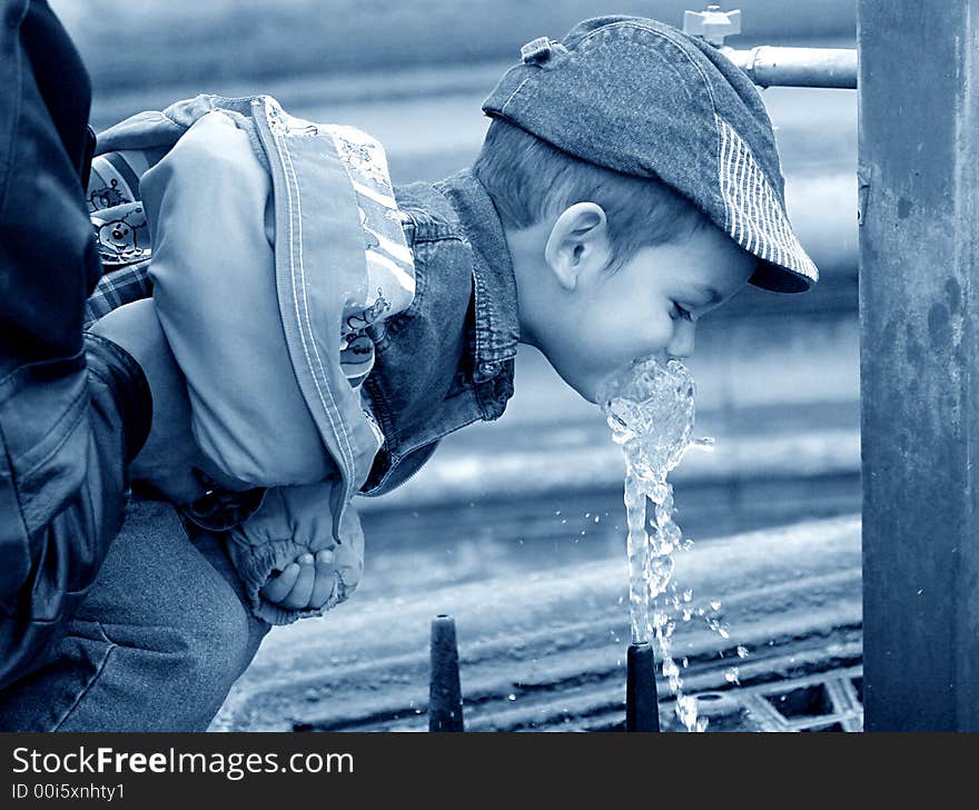 Little boy drinking water from a public fountain