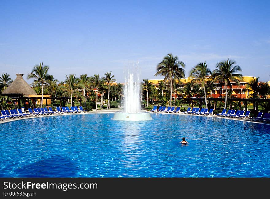 Tropical swimming pool with a lone swimmer in the early morning light.