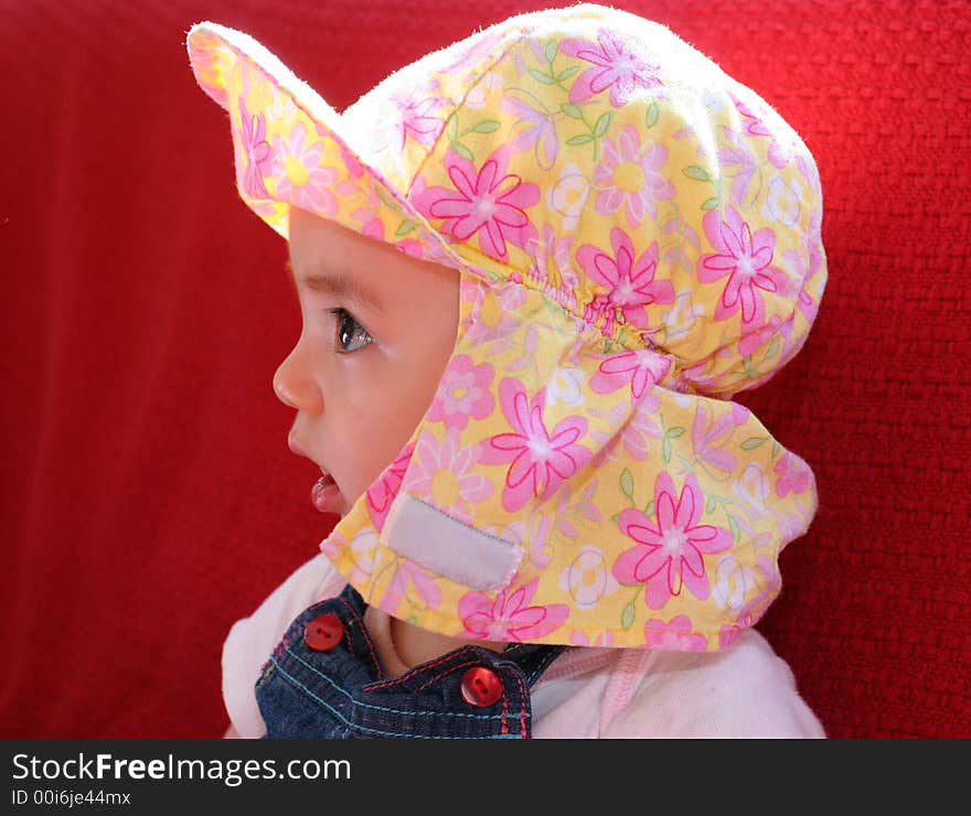 Baby girl in pink flower hat and bib overalls. Baby girl in pink flower hat and bib overalls.