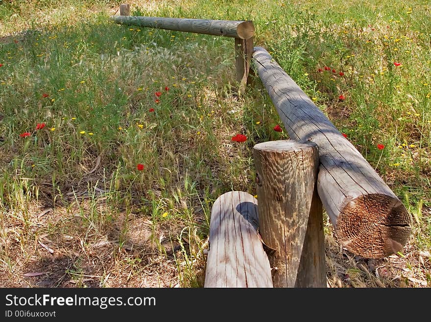 A small fence from logs on a blossoming meadow a log. A small fence from logs on a blossoming meadow a log