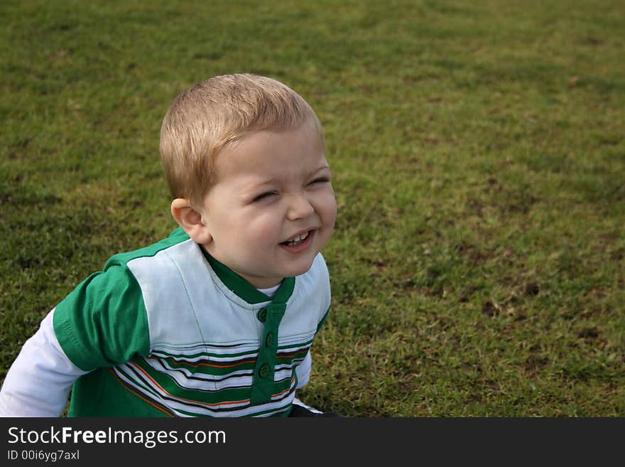 Toddler sitting on the grass, making faces for the camera. Toddler sitting on the grass, making faces for the camera