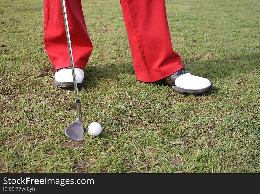 Legs of a male golfer wearing red trousers. Legs of a male golfer wearing red trousers