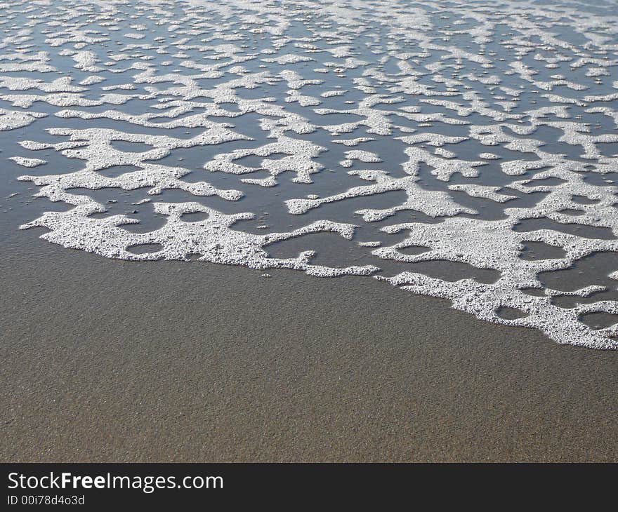 Foam left on a beach by a receding wave. Foam left on a beach by a receding wave