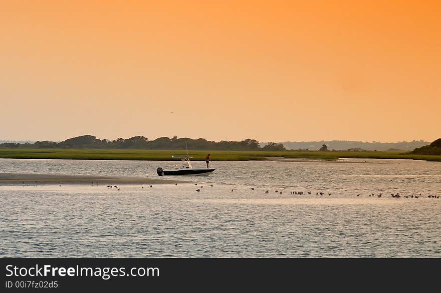 A lone small boat by a sand bar on the sound at low tide in the evening. A lone small boat by a sand bar on the sound at low tide in the evening