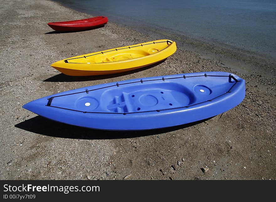 colorful kayaks on beach by turquoise waters