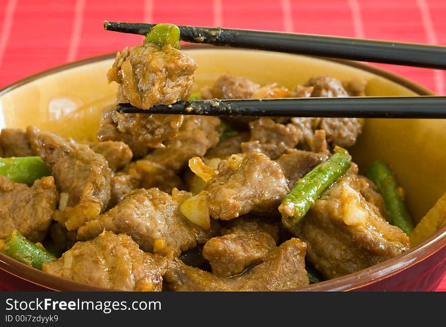 Asian food of beef and vegetables on brown bowl and black chopstick. Asian food of beef and vegetables on brown bowl and black chopstick