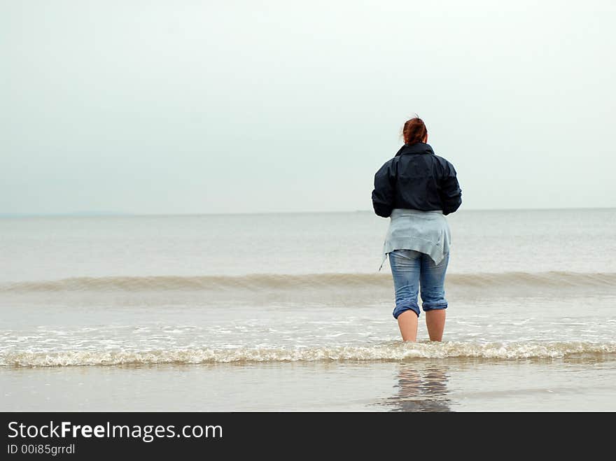 Woman stand in cold sea on empty beach. Woman stand in cold sea on empty beach.