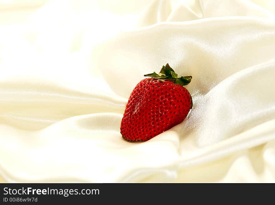 Single strawberry on a cloud of soft white satin