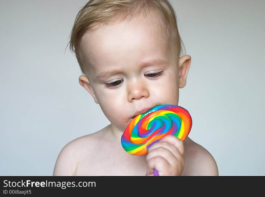 Image of cute toddler licking a colorful lollipop. Image of cute toddler licking a colorful lollipop