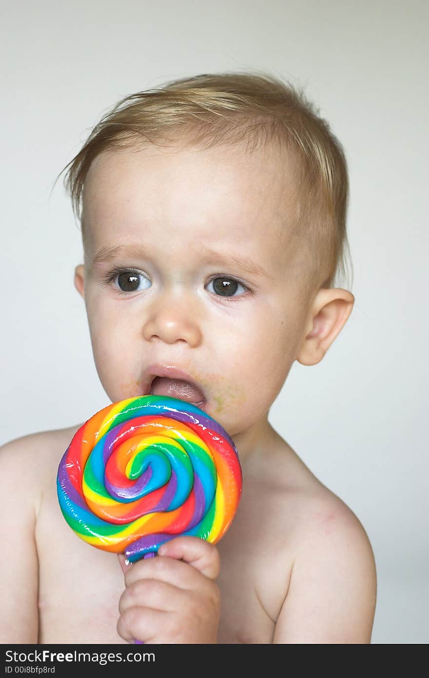 Image of cute toddler licking a colorful lollipop. Image of cute toddler licking a colorful lollipop