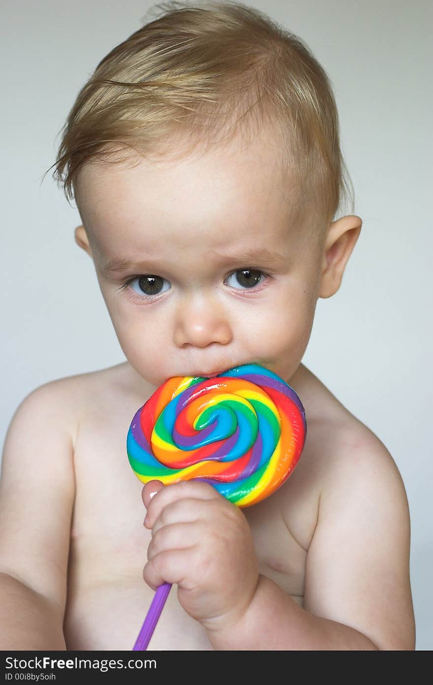 Image of cute toddler licking a colorful lollipop. Image of cute toddler licking a colorful lollipop