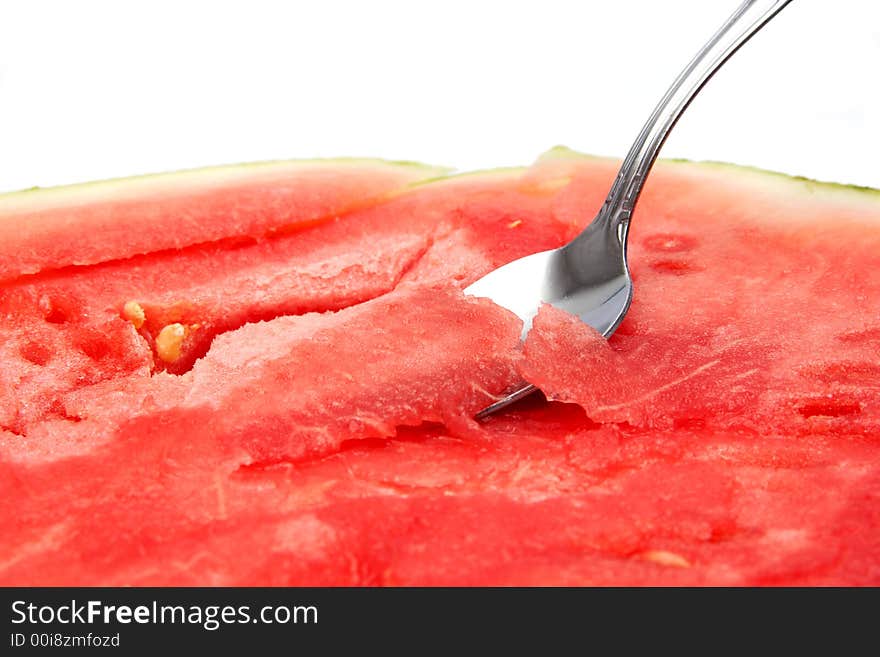 Close-up of a spoon dipping into a juicy watermelon. Focus on the spoon.