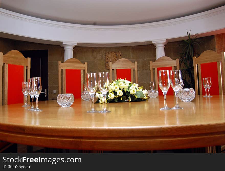 Glasses and vase with flowers on a table in a hall for reception of visitors