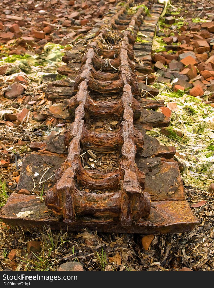 Old rusty bulldozer track among broken bricks