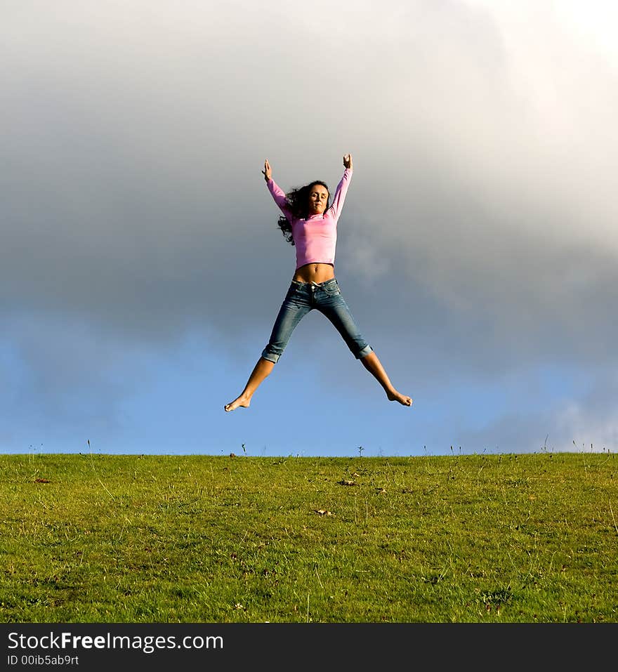 Happy young beautiful girl jumping in the green field. Happy young beautiful girl jumping in the green field.