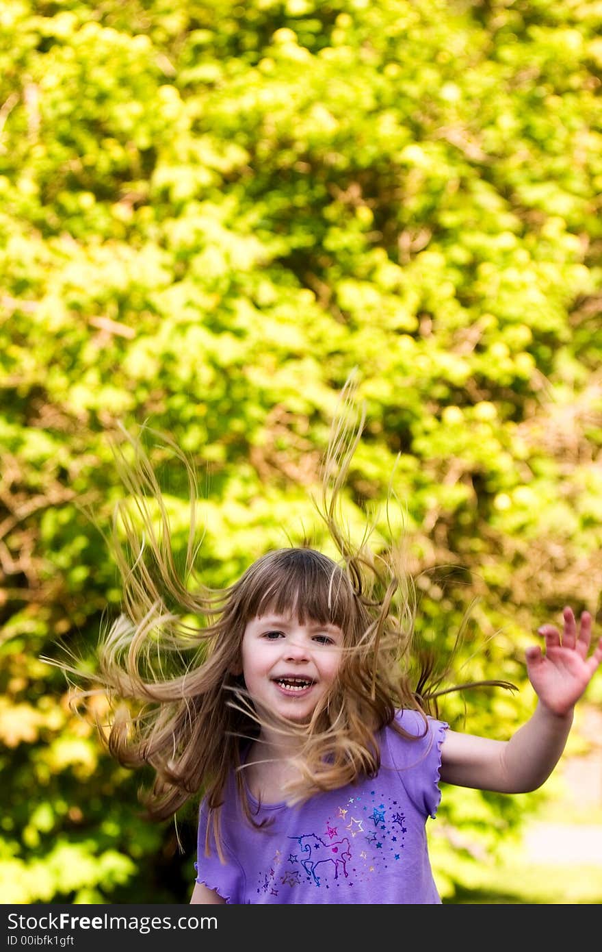 Happy little girl on down-side of a jump, her hair flying high. Happy little girl on down-side of a jump, her hair flying high.