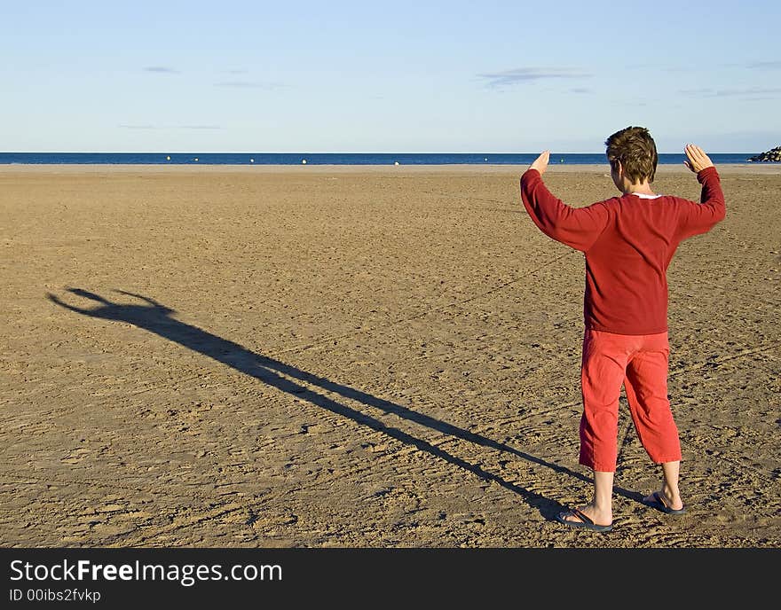 Woman in red clothes making a shadow at sunset on the beach. Woman in red clothes making a shadow at sunset on the beach