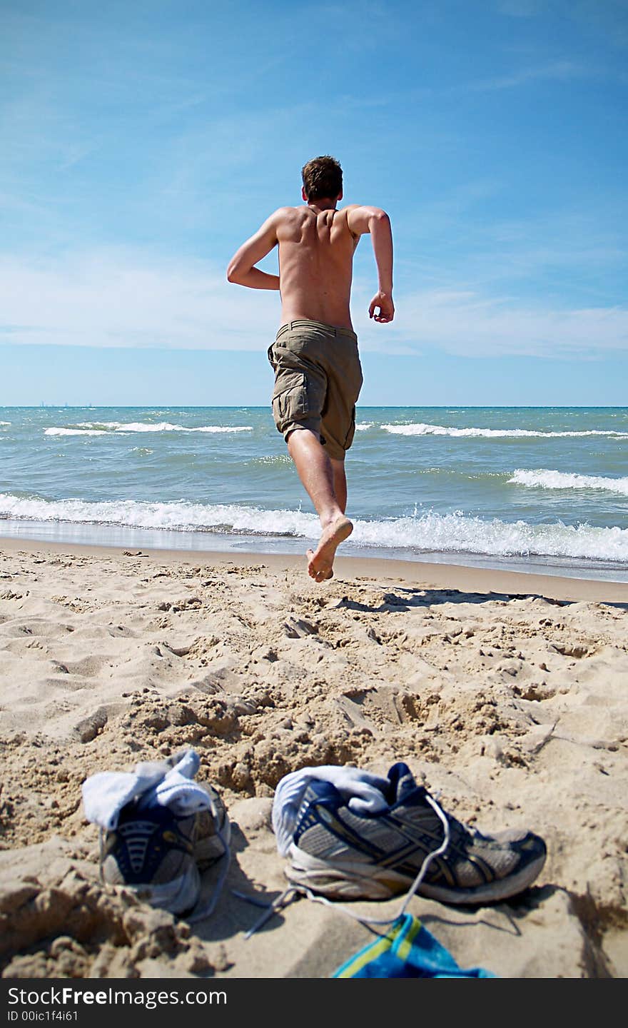 A boy teen runs towards the ocean. A boy teen runs towards the ocean