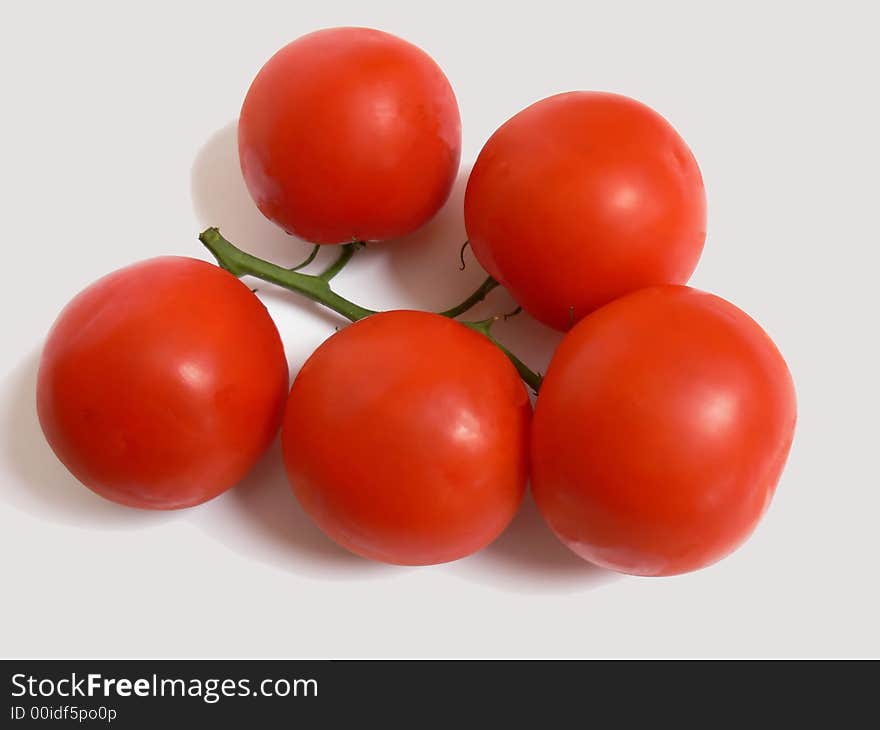 A bunch of ripe red tomatoes still together on the stem on white background.