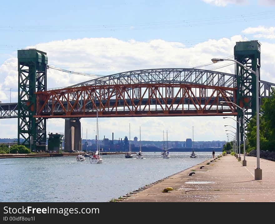 An lifted up lift bridge over the canal to the harbor of Hamilton with sparkling water waves and several small sailboats.