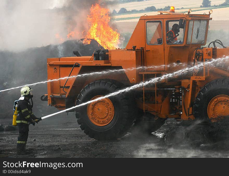 Two Firemen and a digger fighting the fire of tires