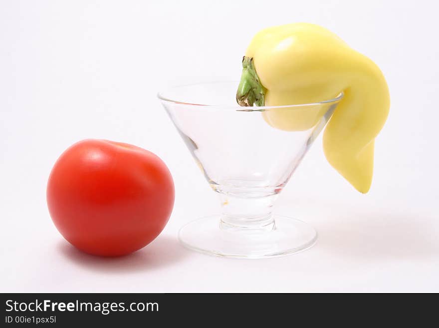 Tomato and a yellow paprika in a cocktail glass on a white background