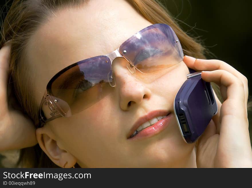 Portrait of the young girl in glasses speaking by phone. Portrait of the young girl in glasses speaking by phone