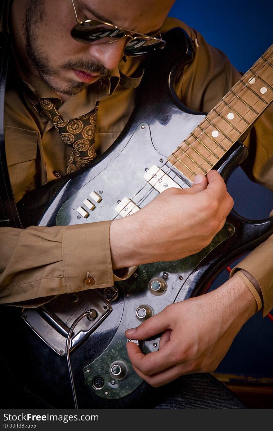 Rocker getting ready to play, adjusting his guitar, looking for the perfect sound. Close framing on the subject. Rocker getting ready to play, adjusting his guitar, looking for the perfect sound. Close framing on the subject.