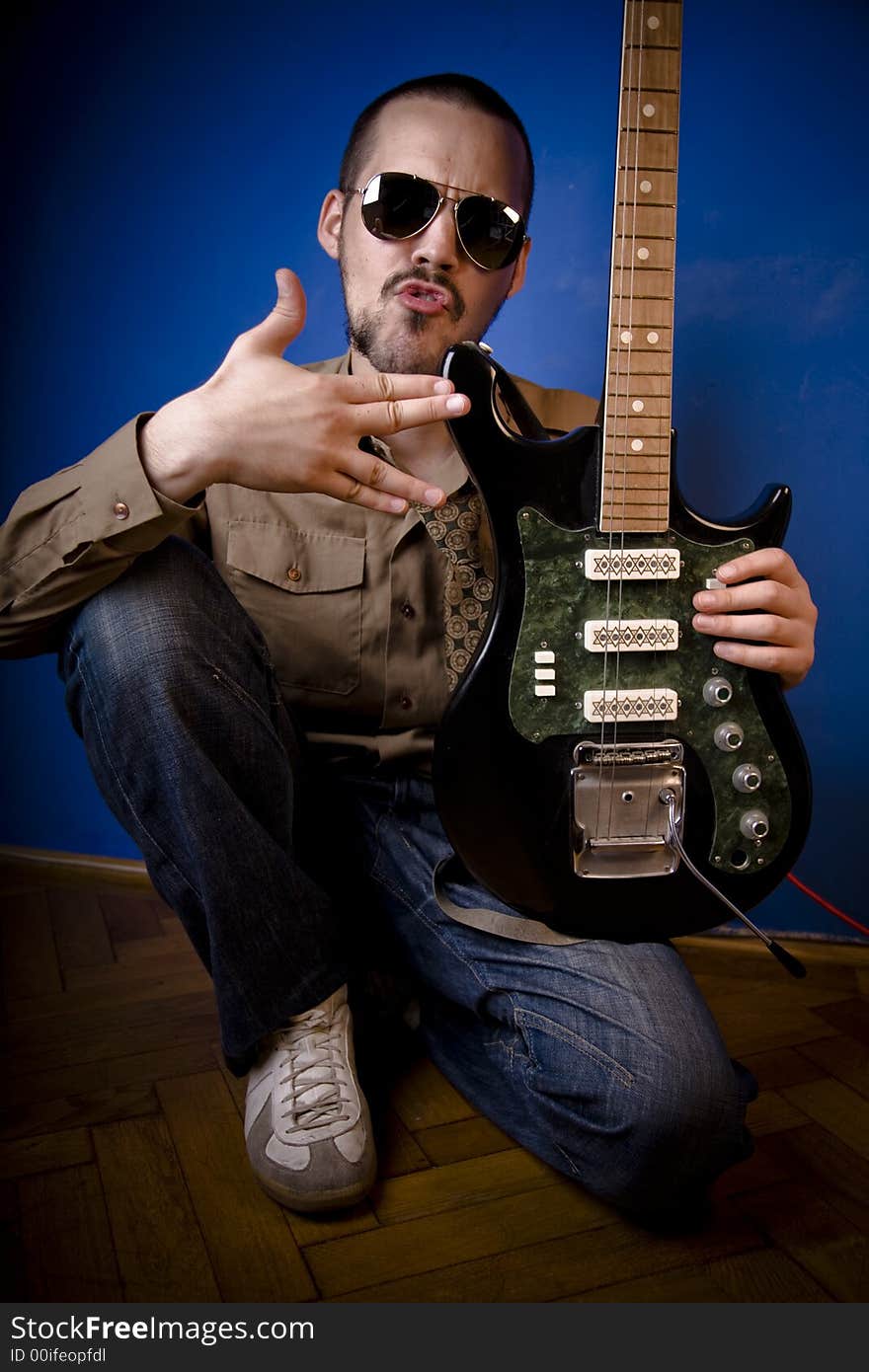 Guitar player with sunglasses in studio, posing with his guitar. Guitar player with sunglasses in studio, posing with his guitar.