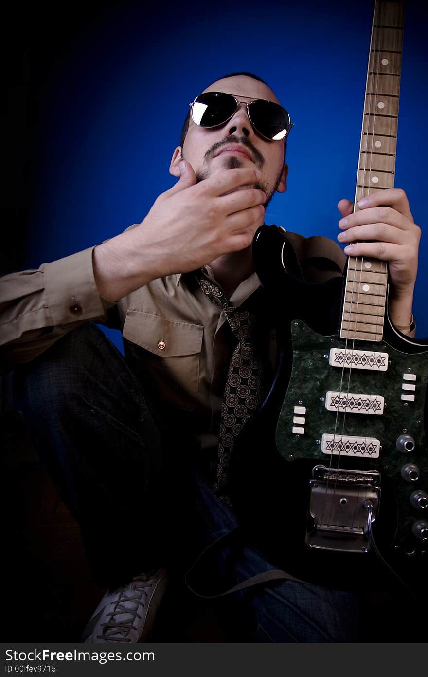 Guitar player with sunglasses in studio, looking smugly at the camera. Guitar player with sunglasses in studio, looking smugly at the camera.