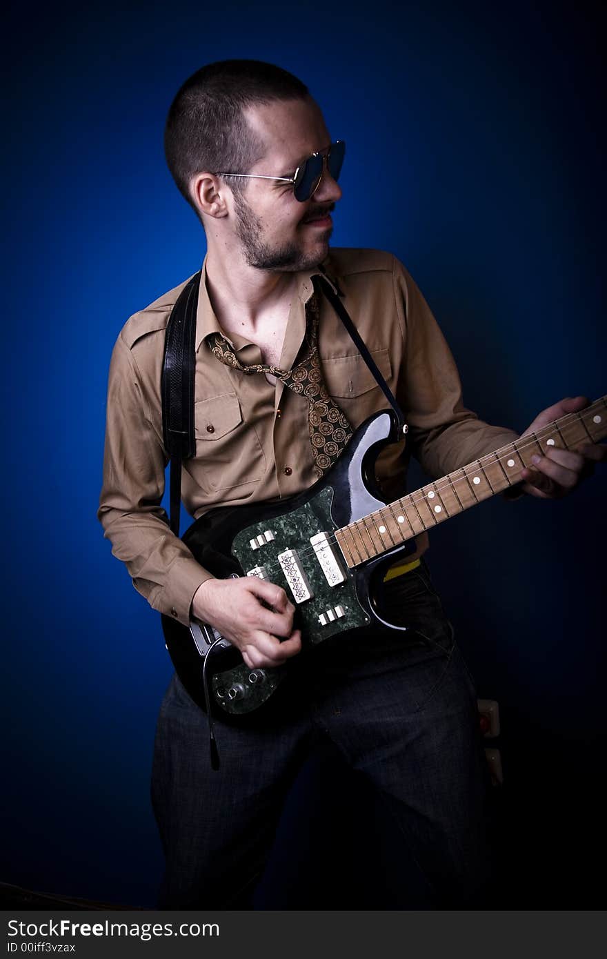 Guitar player with sunglasses in studio, jamming. Blue background. Guitar player with sunglasses in studio, jamming. Blue background.