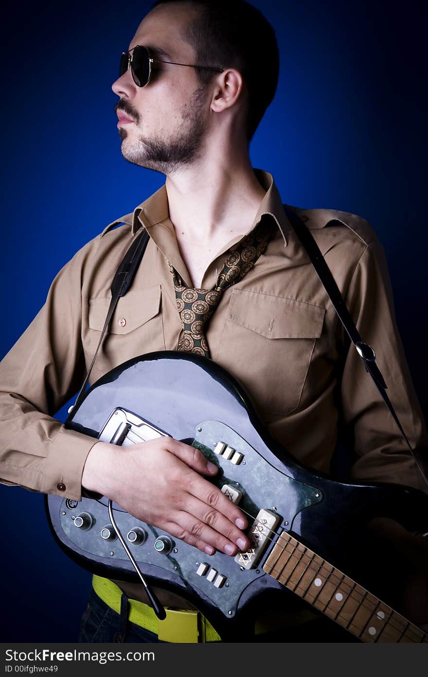 Electric guitar player with sunglasses in studio against a blue wall. Electric guitar player with sunglasses in studio against a blue wall.