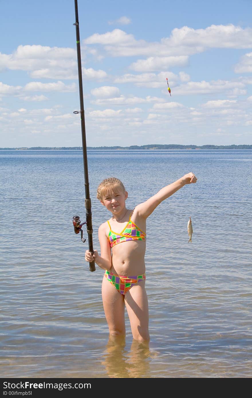 Girl holding a fish caught on a fishing line with clouds. Girl holding a fish caught on a fishing line with clouds