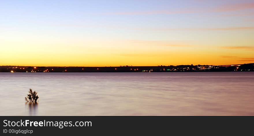 Dusk over water looking onto houses in the distance. Dusk over water looking onto houses in the distance